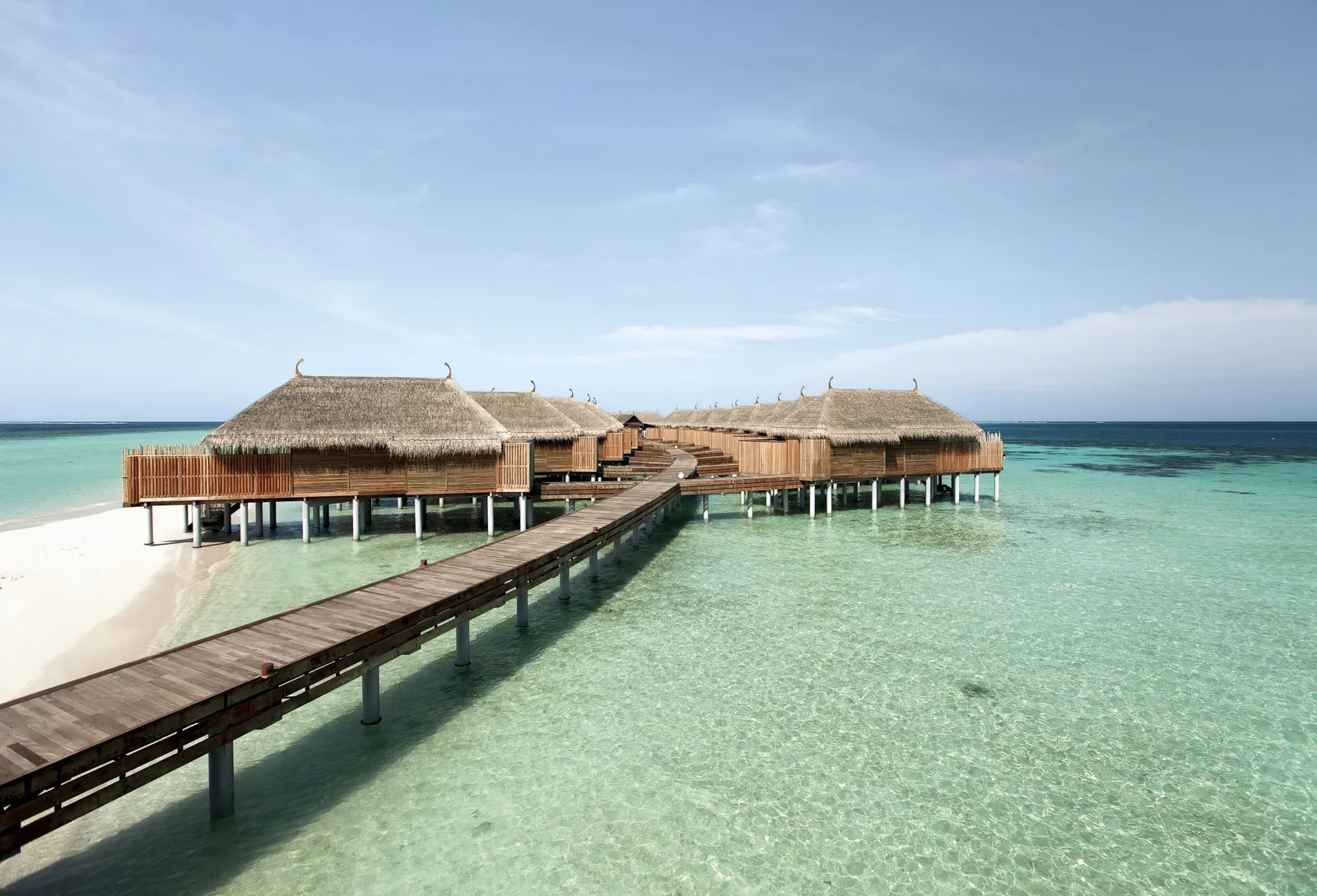 The wooden jetty from the beach to the water villas, over a clear lagoon