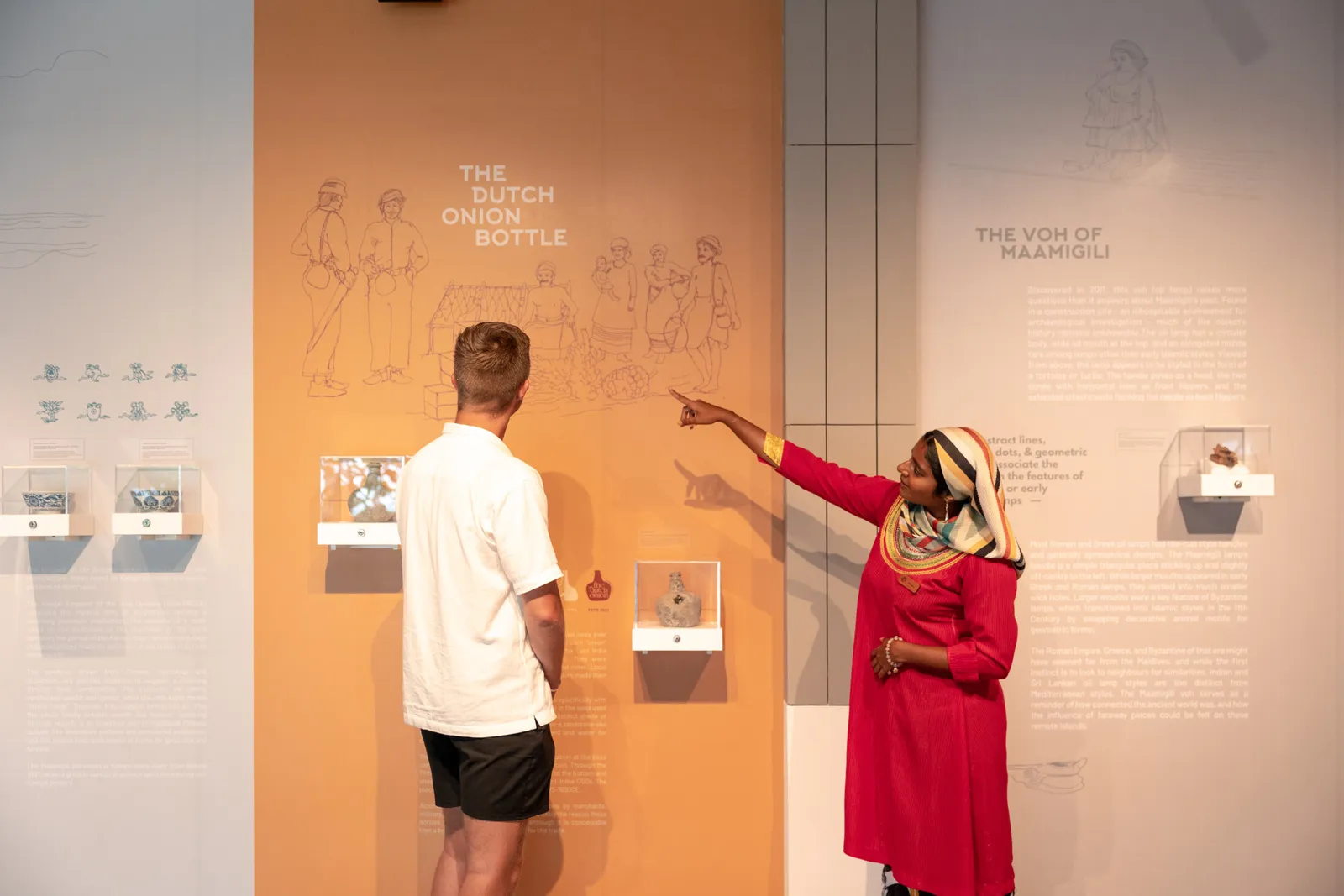 In the museum gallery in the lobby, a guide in traditional dress shows a guest the island’s finds.