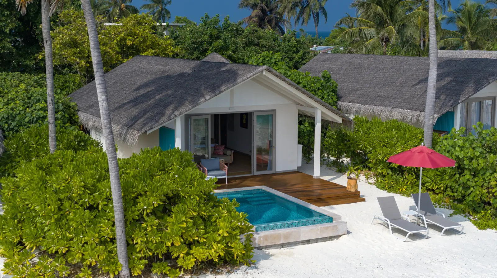 A Beach Pool Villa from above: the thatched house, its private pool and loungers on the sand among the green.