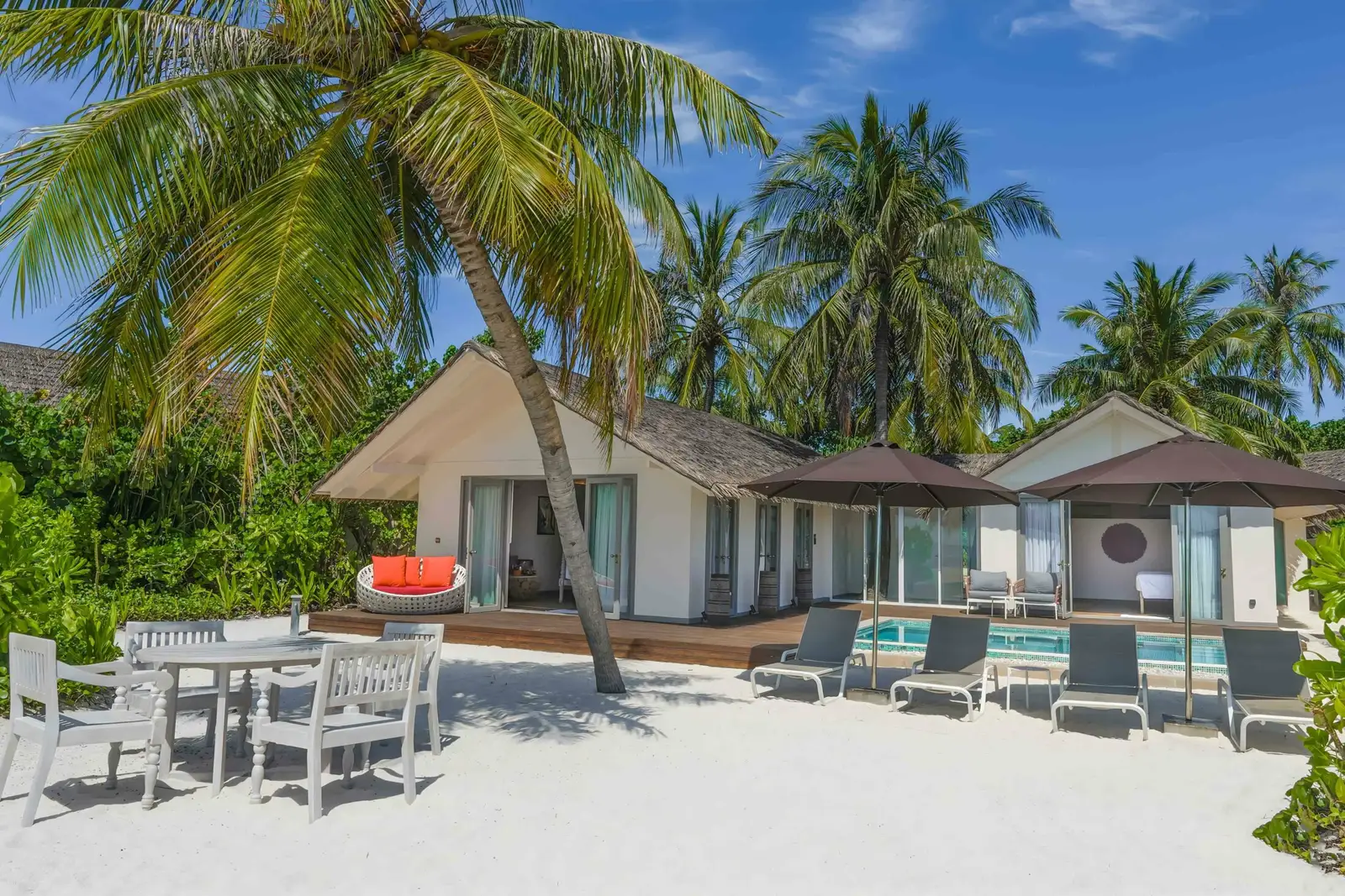 The Two Bedroom Beach Pool Suite on the beach, with its outdoor table, loungers and pool under the palms.