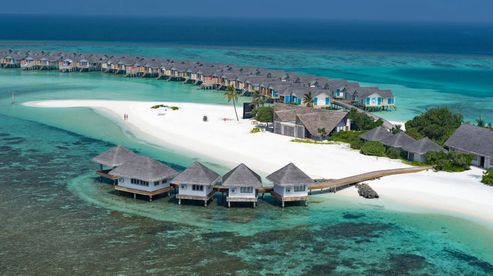 From above, the spa’s overwater rooms in a row beside the beach, with the jetty of lagoon villas behind.