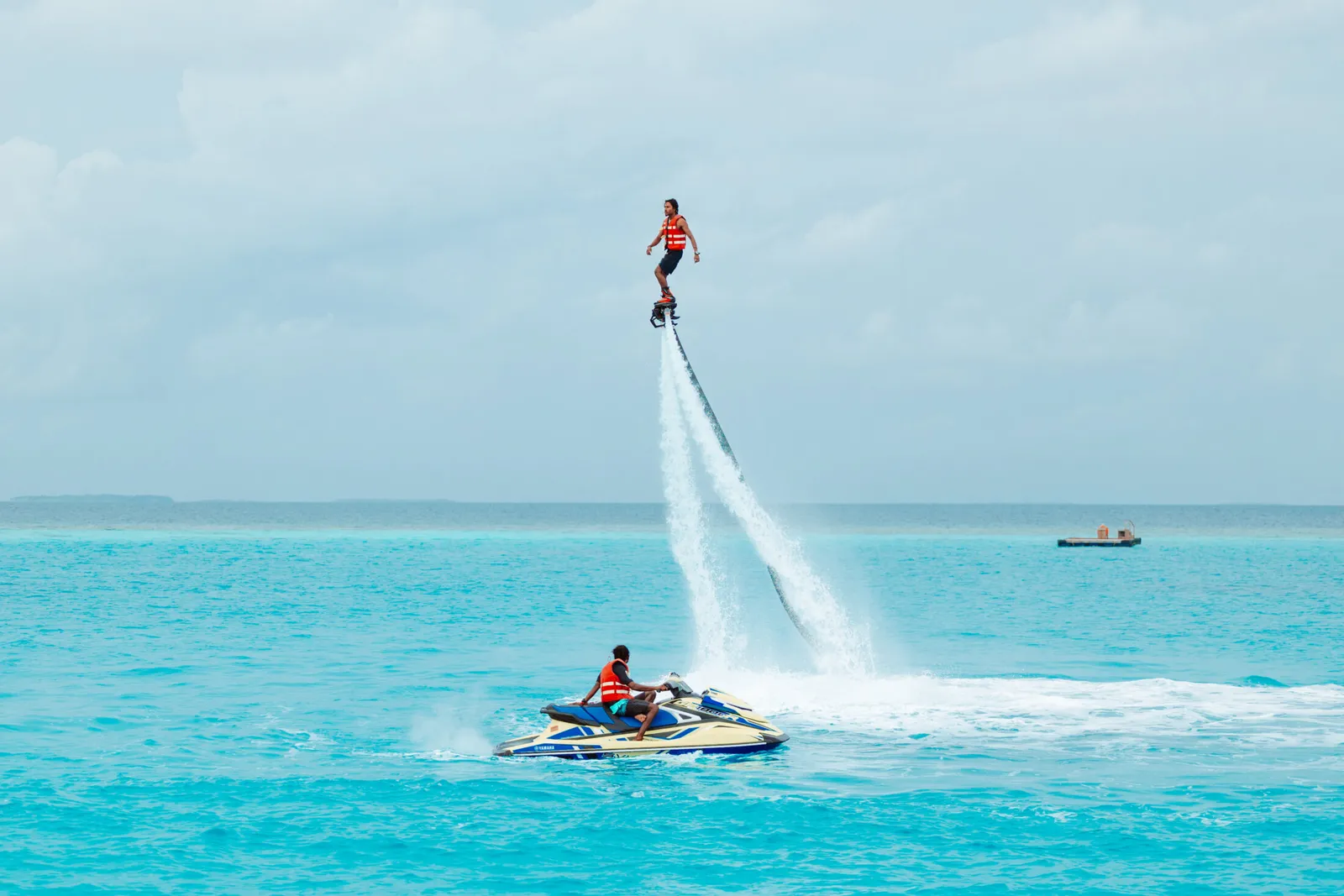 In the lagoon one person rides a flyboard’s jet and another drives the jet ski.