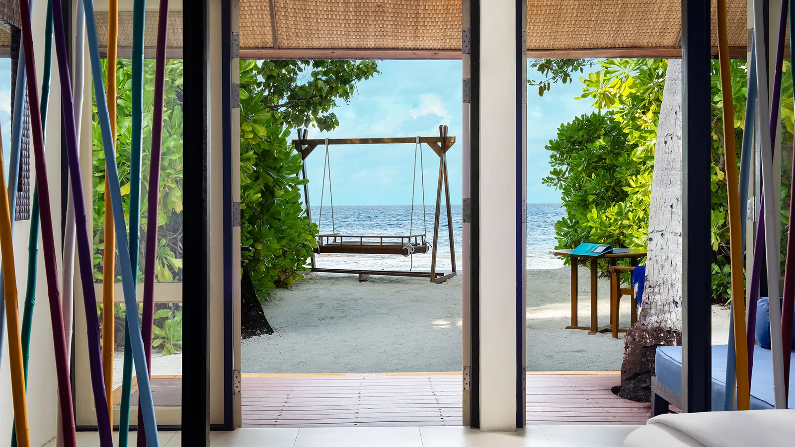 From a Beachfront Rainmist Villa’s bedroom, through the open doors: the veranda, the swing and the beach.