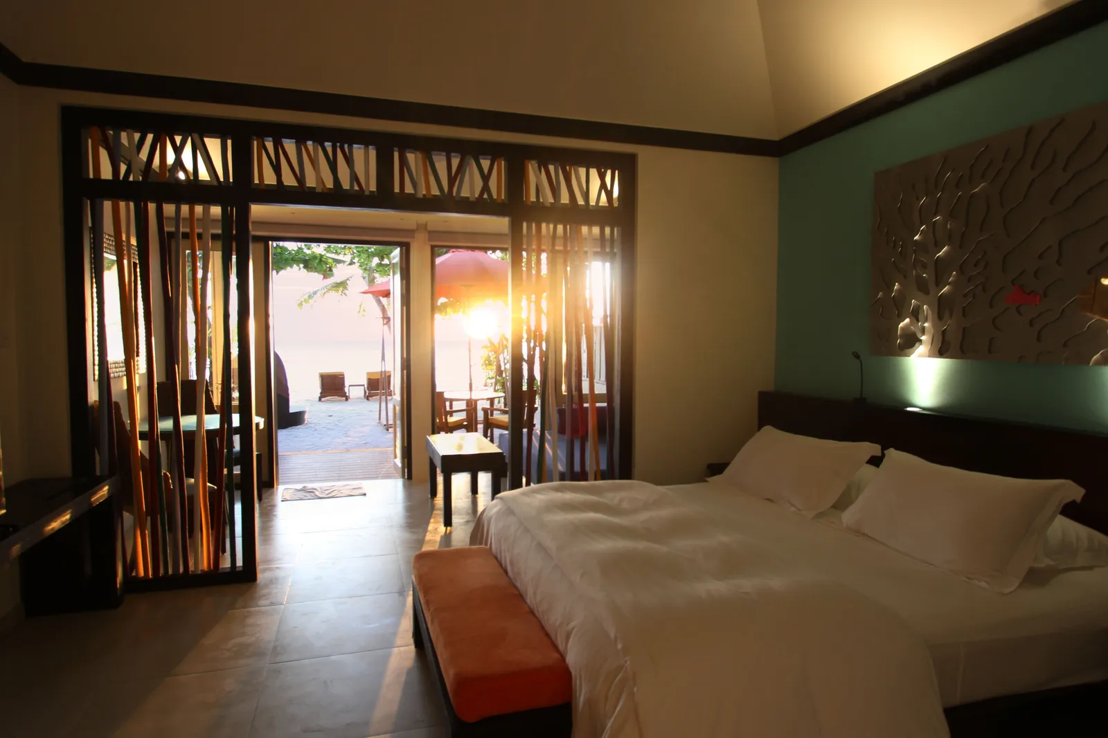 A Beachfront Sunset Villa’s bedroom: the king bed, the turquoise wall and the sunset beyond the doors open onto the veranda.