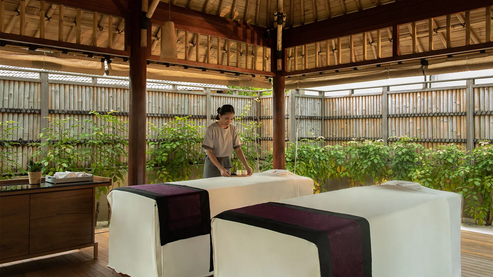 An 8lements Spa room: 2 treatment beds under a pavilion open to the garden, behind a bamboo fence.