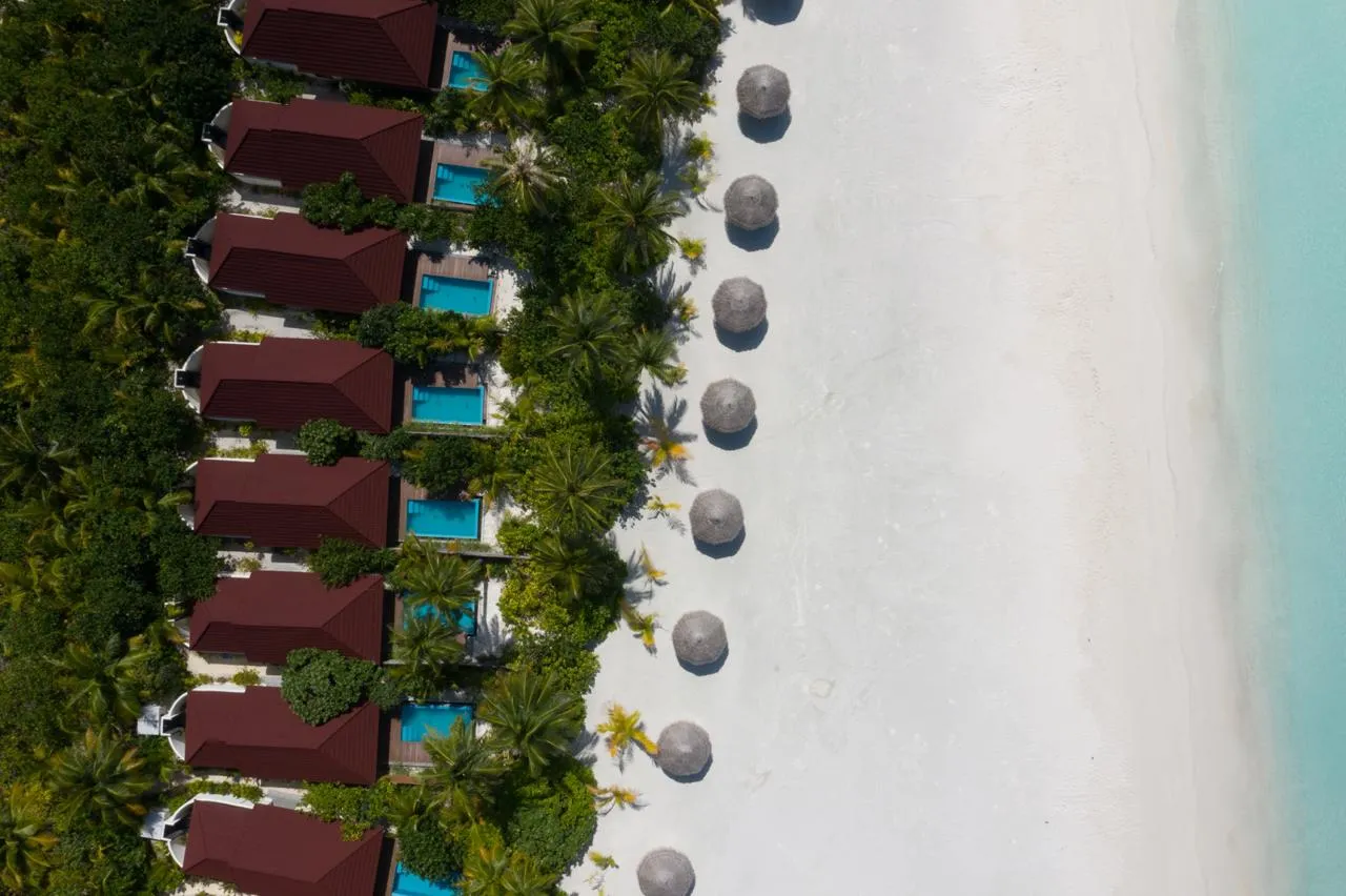 The Pool Beach Villas from above: red roofs, plunge pools and thatched parasols on the sand.