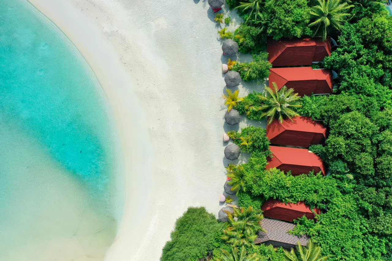 The Beach Villas from above: red roofs among the palms, a few steps from the white beach.
