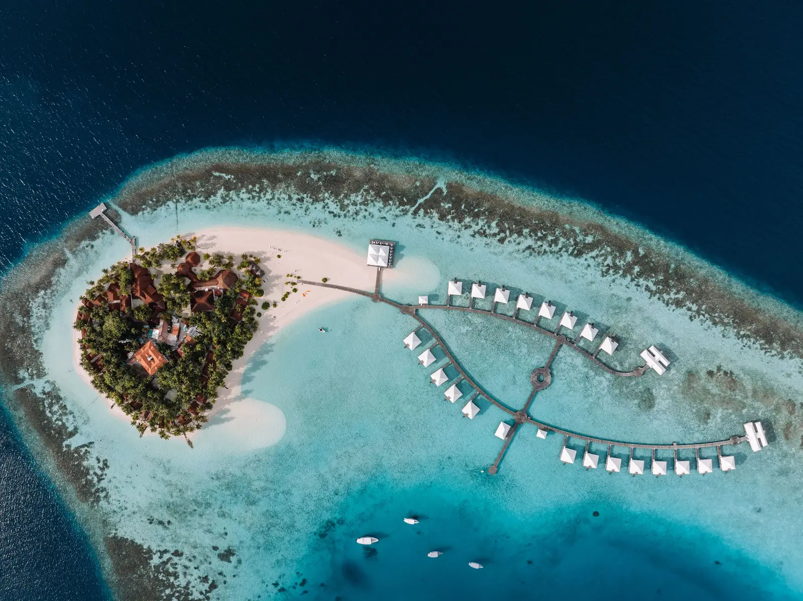 Athuruga from above: the round green island, its spit of sand and the 2 rows of water villas in the lagoon.