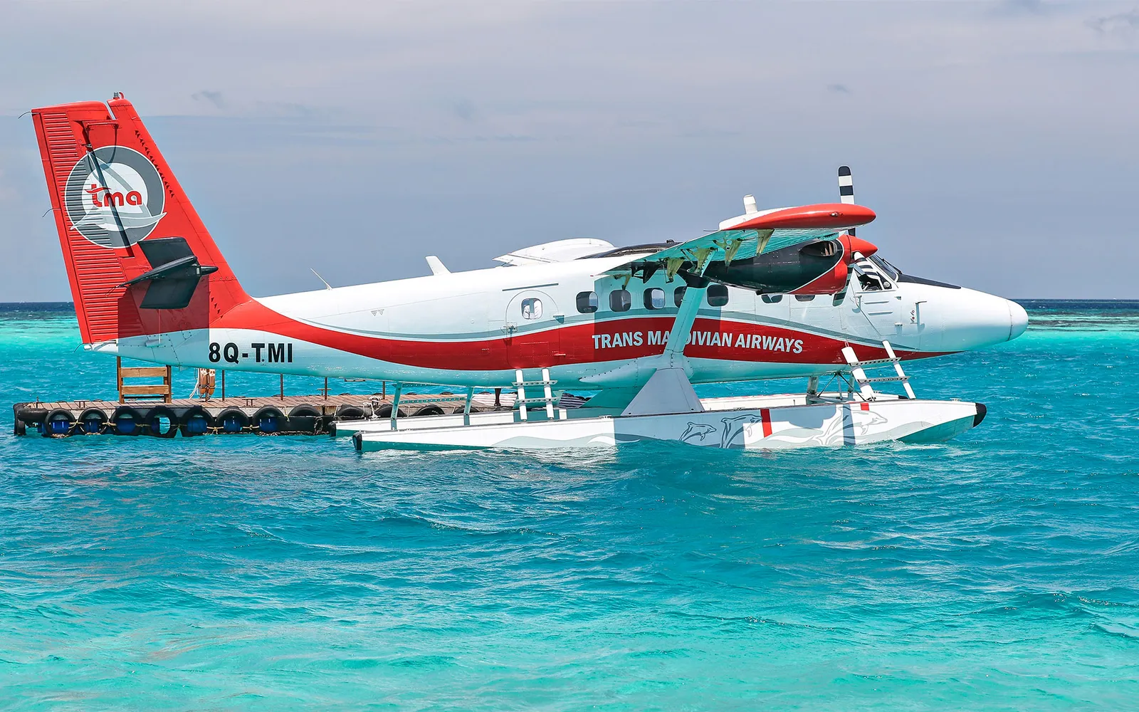 Trans Maldivian Airways’ red and white seaplane moored on the turquoise lagoon.