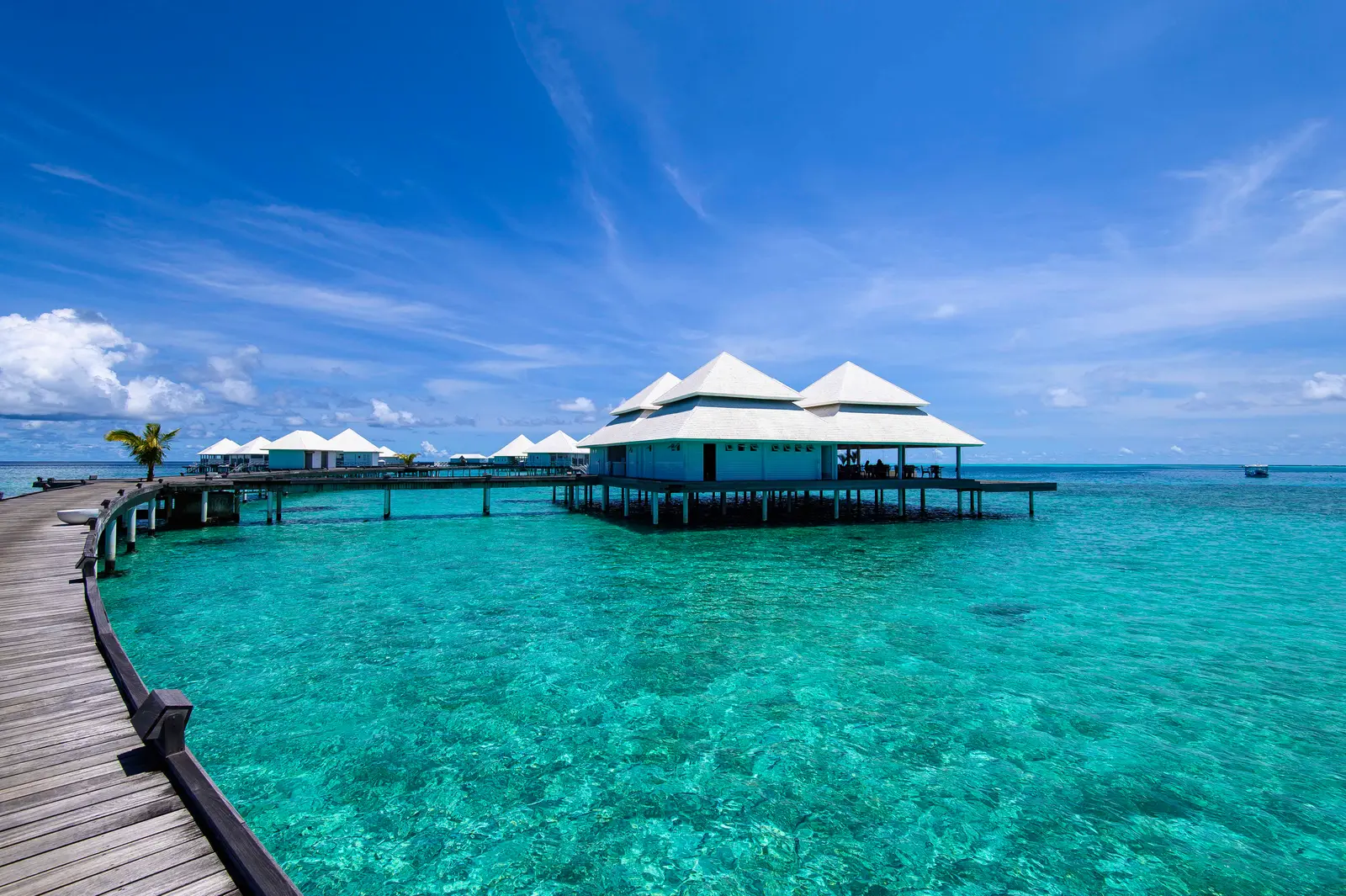 The wooden jetty out to Aqua and the water villas, over the turquoise lagoon.