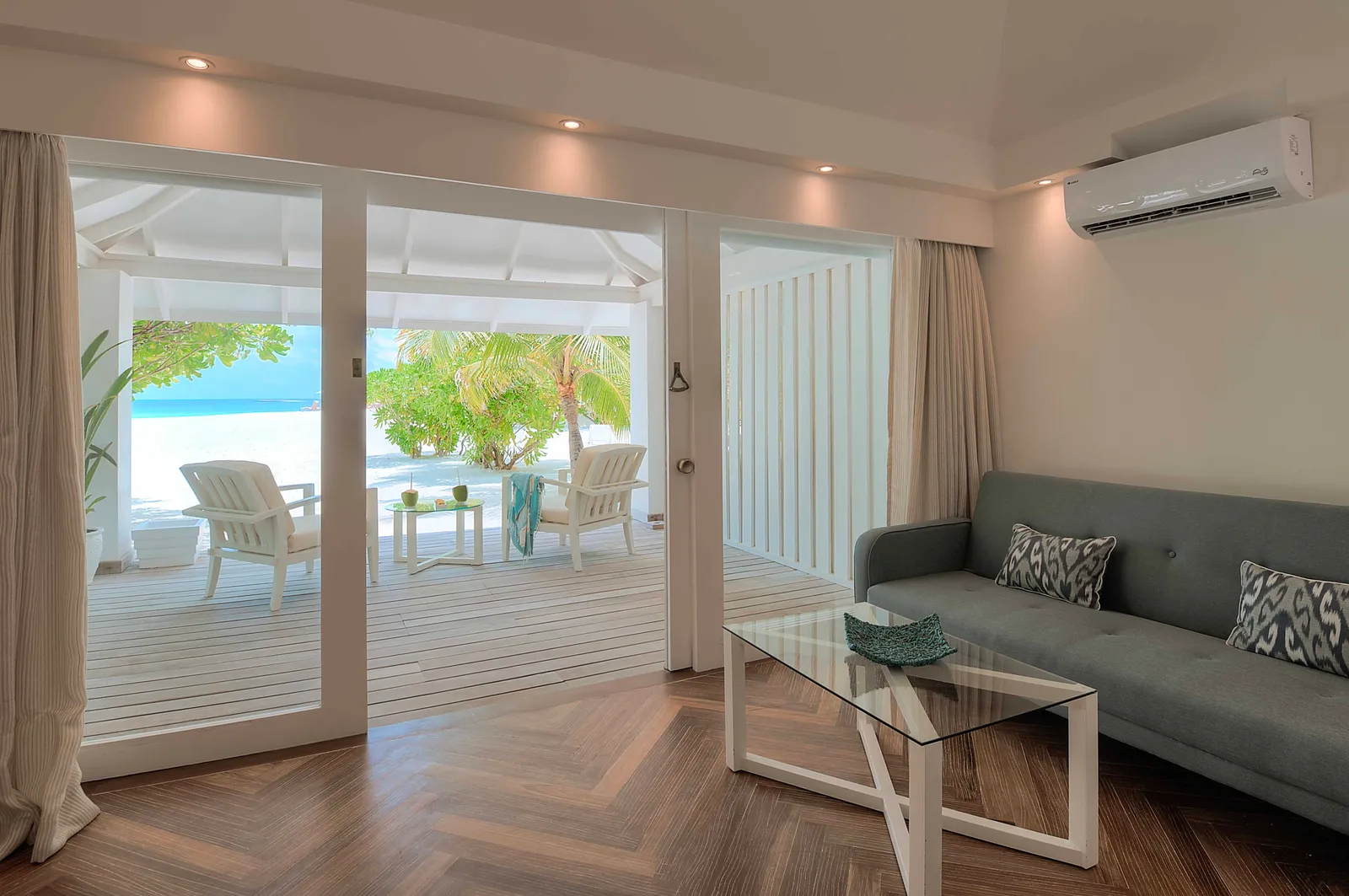 A Beach Front Junior Suite’s living area: the sofa, the glass table and the doors open onto the veranda.