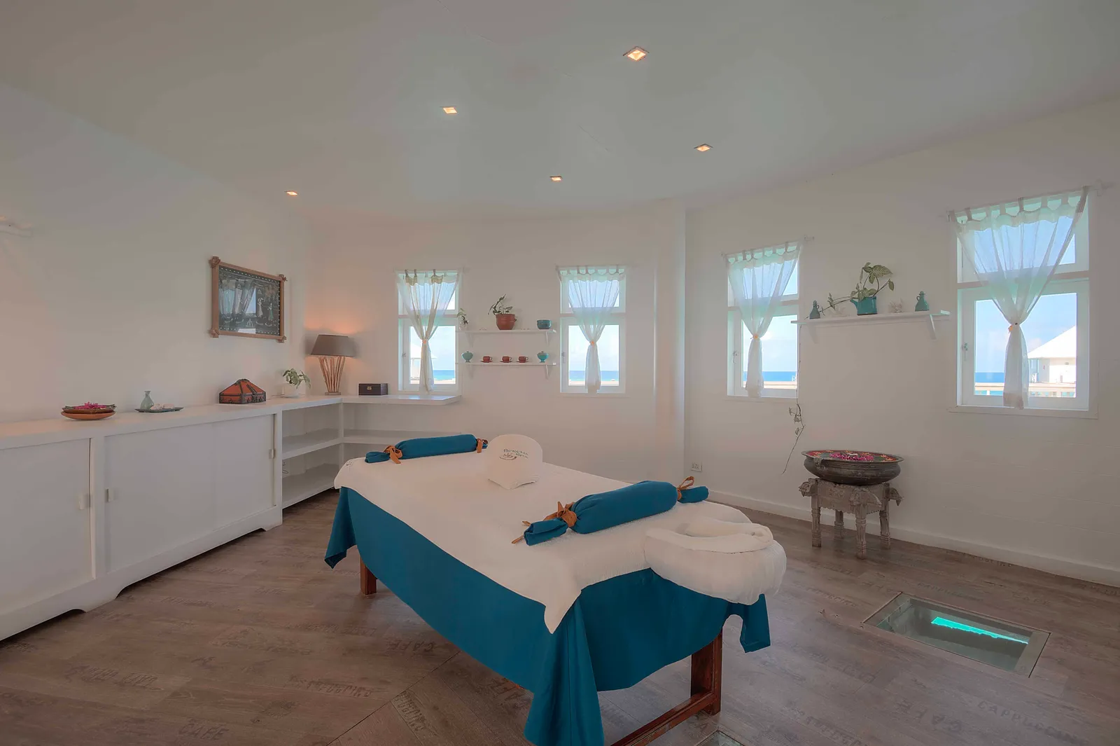 A Serena Spa treatment room: the massage table, windows onto the lagoon and a glass panel in the floor over the sea.