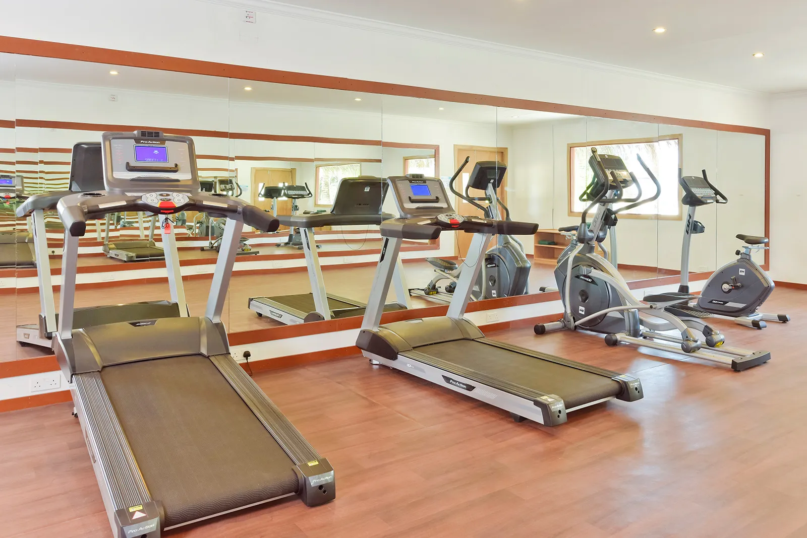 The gym with its treadmills, cross-trainer and machines in front of the mirrors.