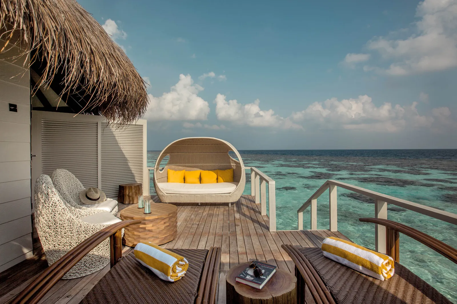 A Water Villa’s deck, with its round daybed, the loungers and the rail above the lagoon.