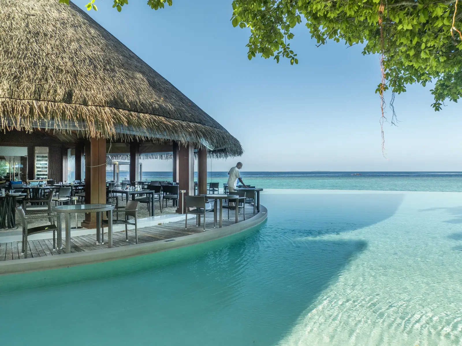 The Sea Grill’s thatched pavilion on the rim of the infinity pool, tables laid and the turquoise sea beyond.