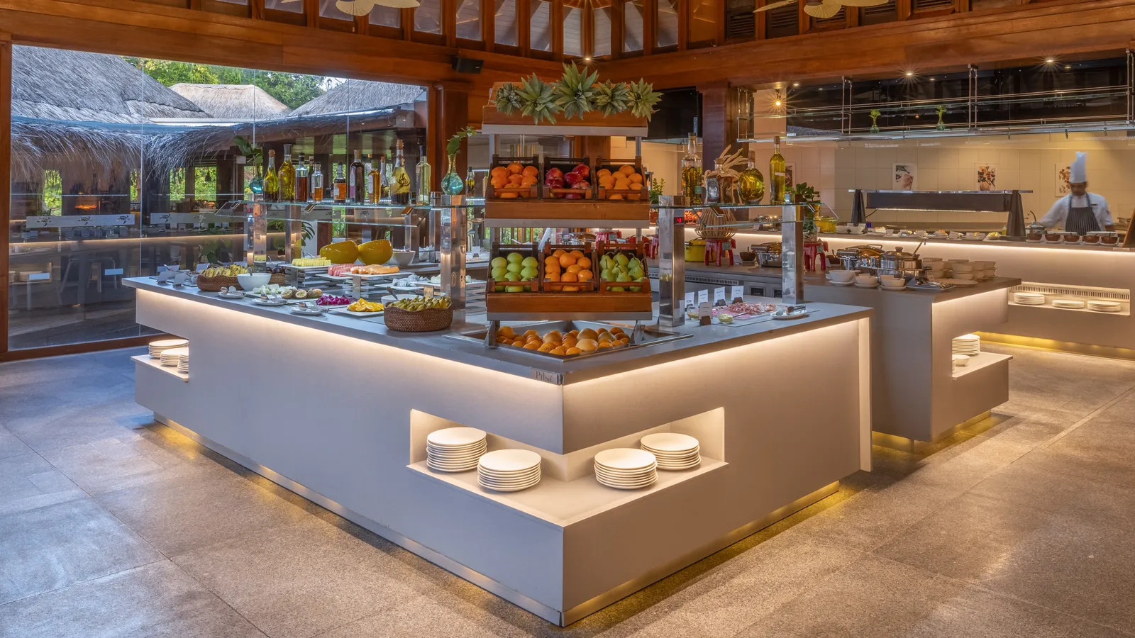 The Market’s buffet, with fruit and bread and a chef at work in the kitchen.