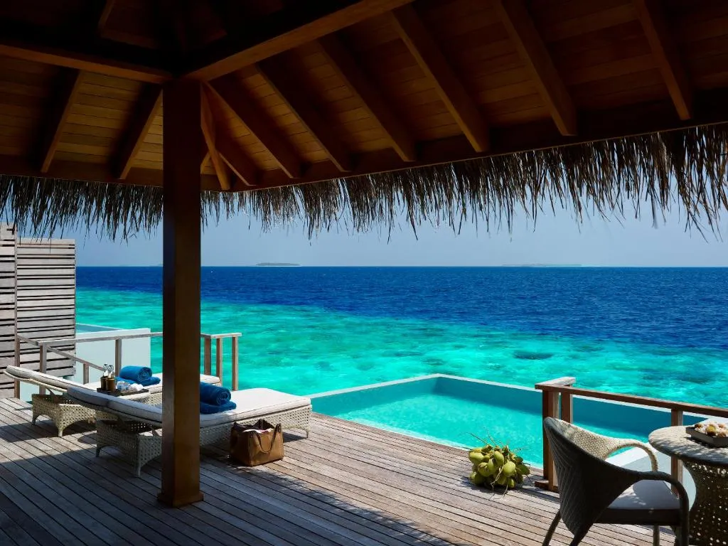 The deck of a Waterfront Pool Villa, with its pool, loungers and the turquoise lagoon.