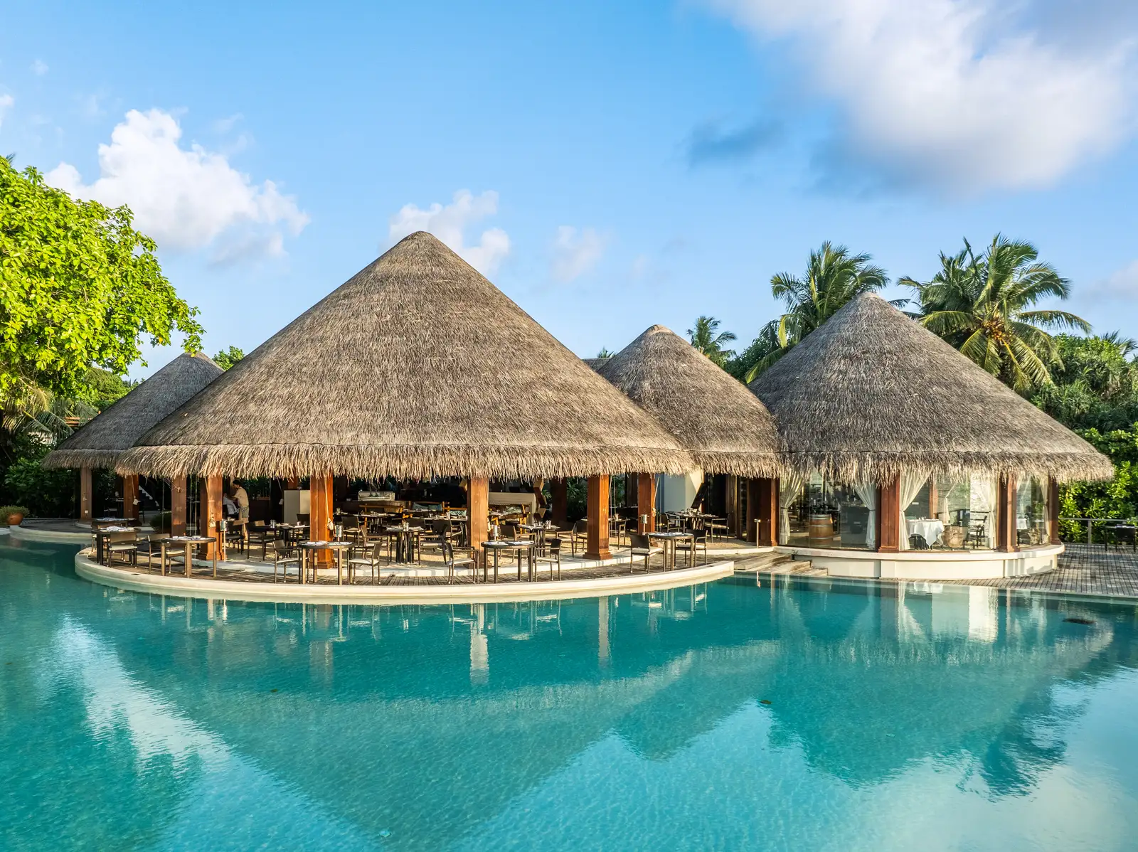 The Sea Grill’s 3 thatched pavilions reflected in the pool under a blue sky.