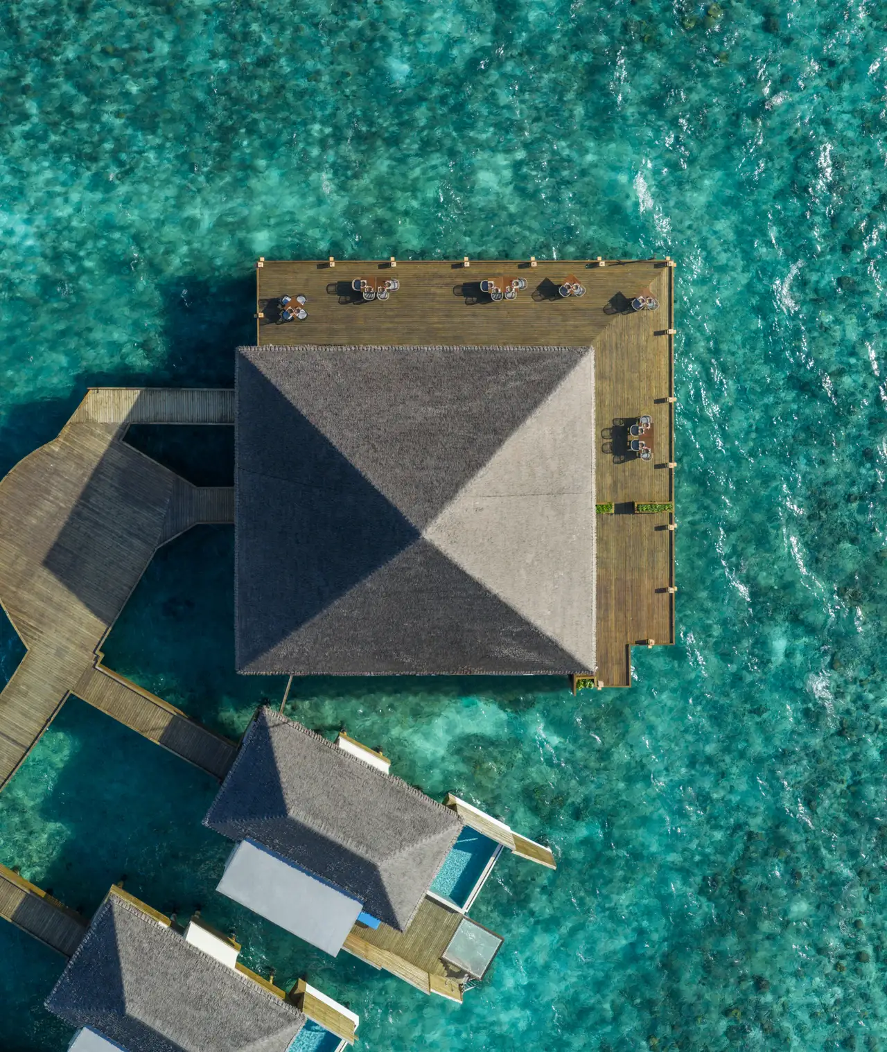 BŌ seen from straight above: its pyramid roof over the lagoon and the walkway joining it to the villas.