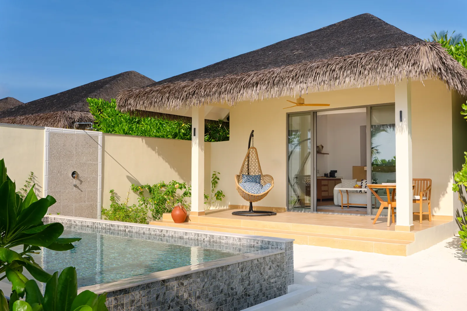 A Beach Pool Villa from outside: the private pool, the terrace under its thatched roof and a hanging chair.