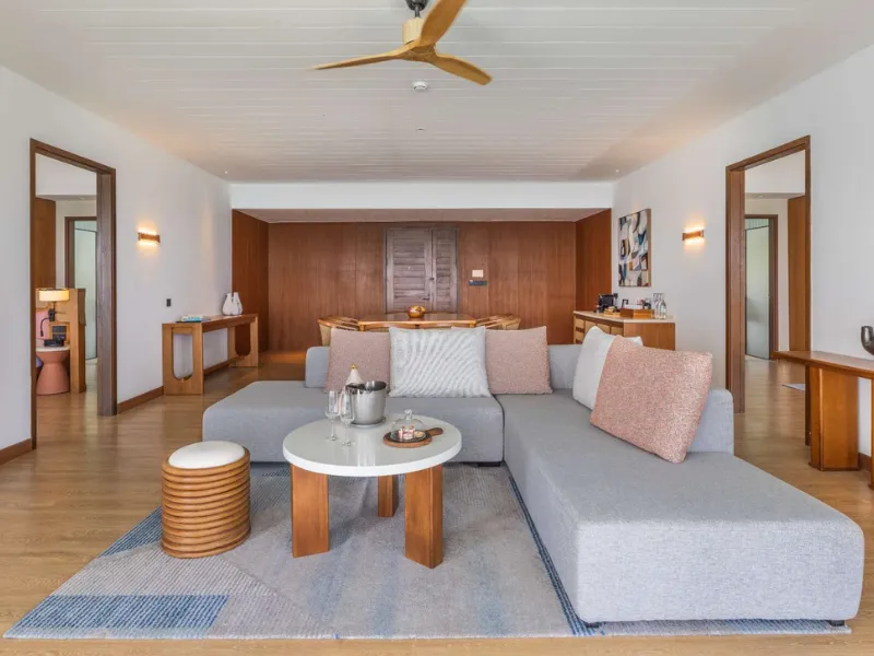 The living room of the Four Bedroom Family Suite: a corner sofa, the dining table and the bedroom doors.