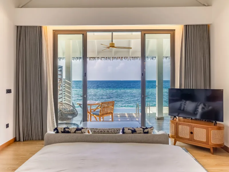 A Premium Overwater Pool Villa: from the bed, beyond the glass, the deck and the open ocean.