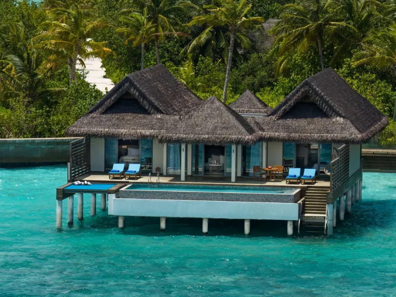 The overwater suite from outside: thatched roofs, the pool on its deck and loungers above the lagoon.