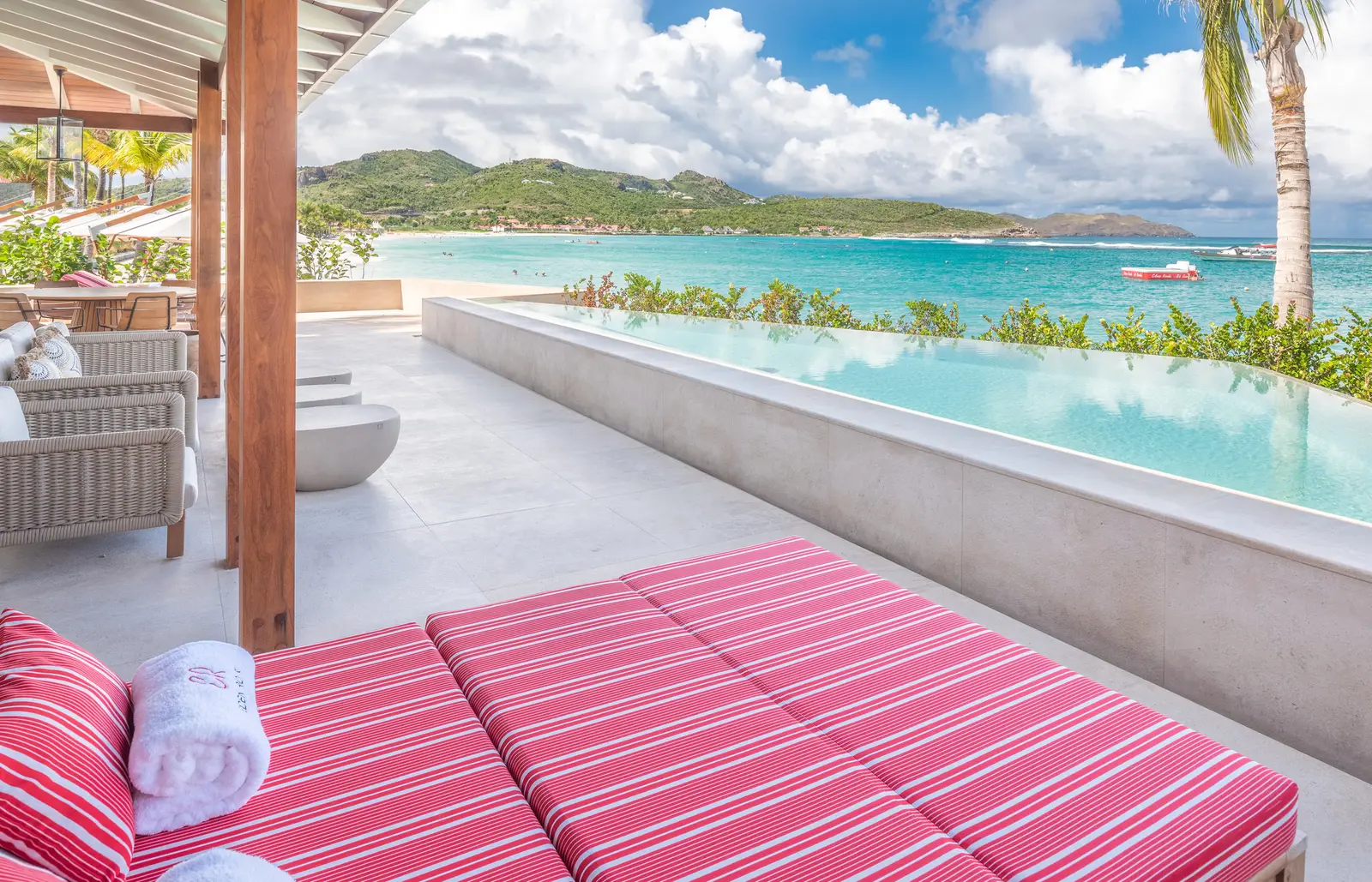 Diamond Suite Waterlily’s terrace: a red-striped daybed, the infinity pool on the beach and the bay.