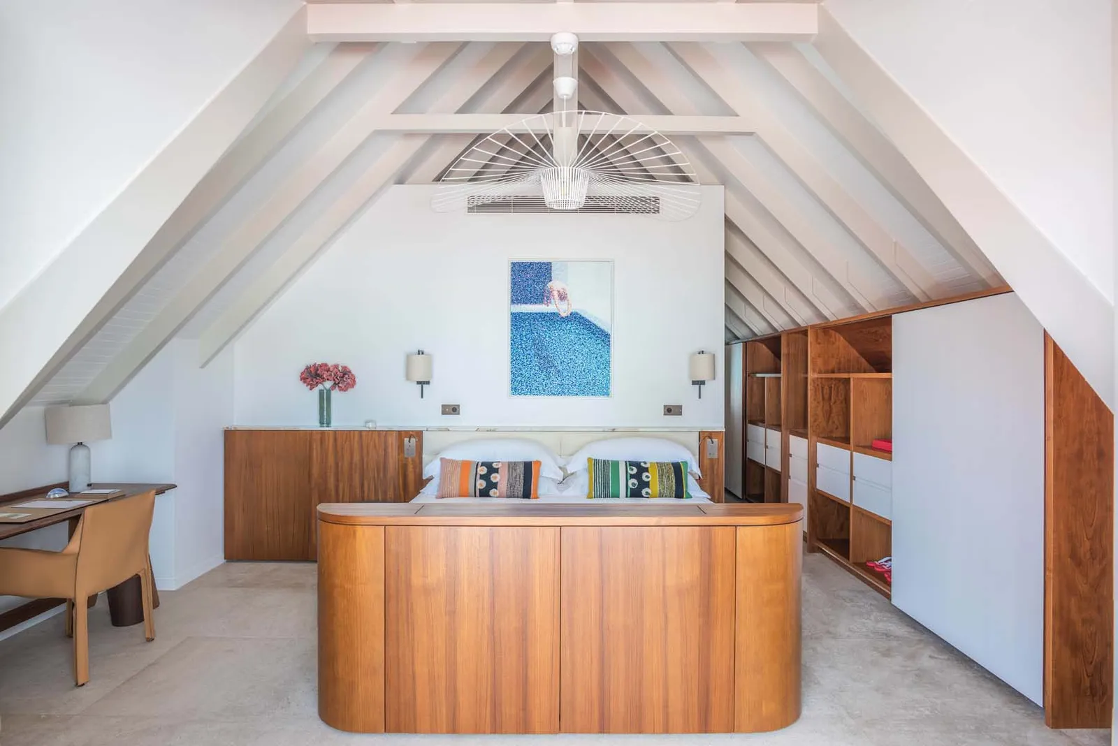 A Heavenly Beach House bedroom under white rafters: the bed in its curved timber surround and a blue picture.