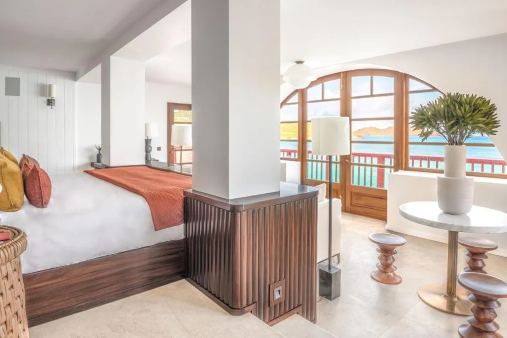 Legacy Suite De Haenen: the bed beside a column, a round table with a plant and the arched window on the bay.