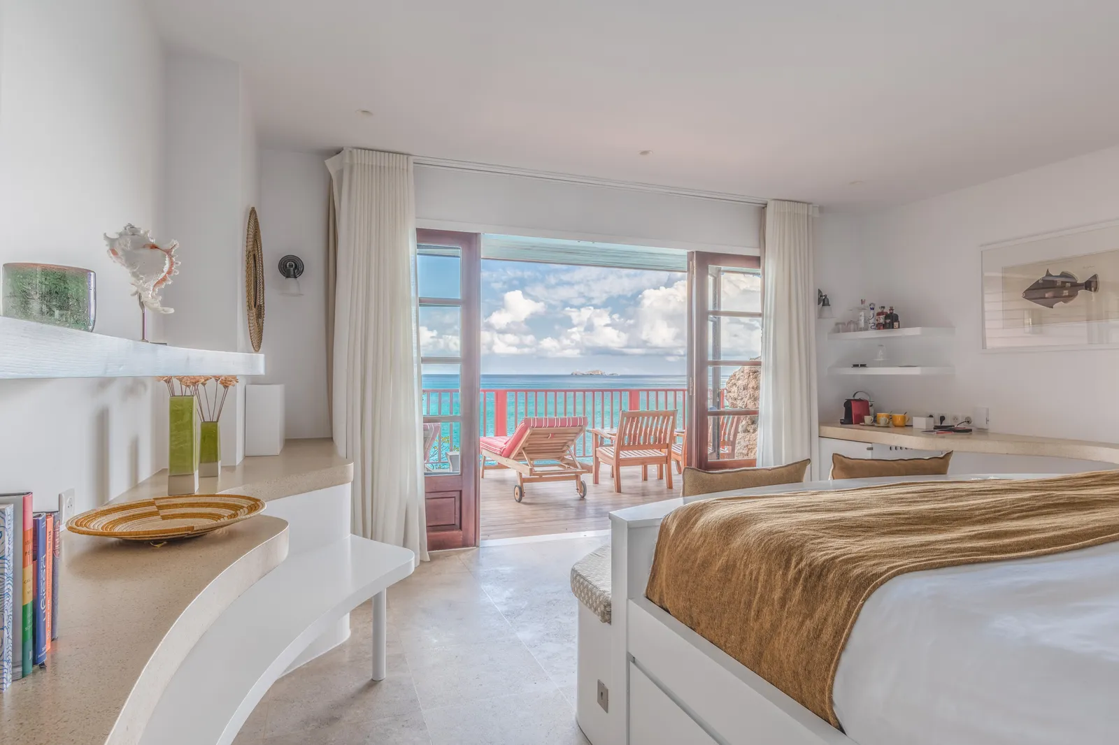 A Rock Room: white curved fittings, the bed and doors open to a terrace with loungers and the sea.