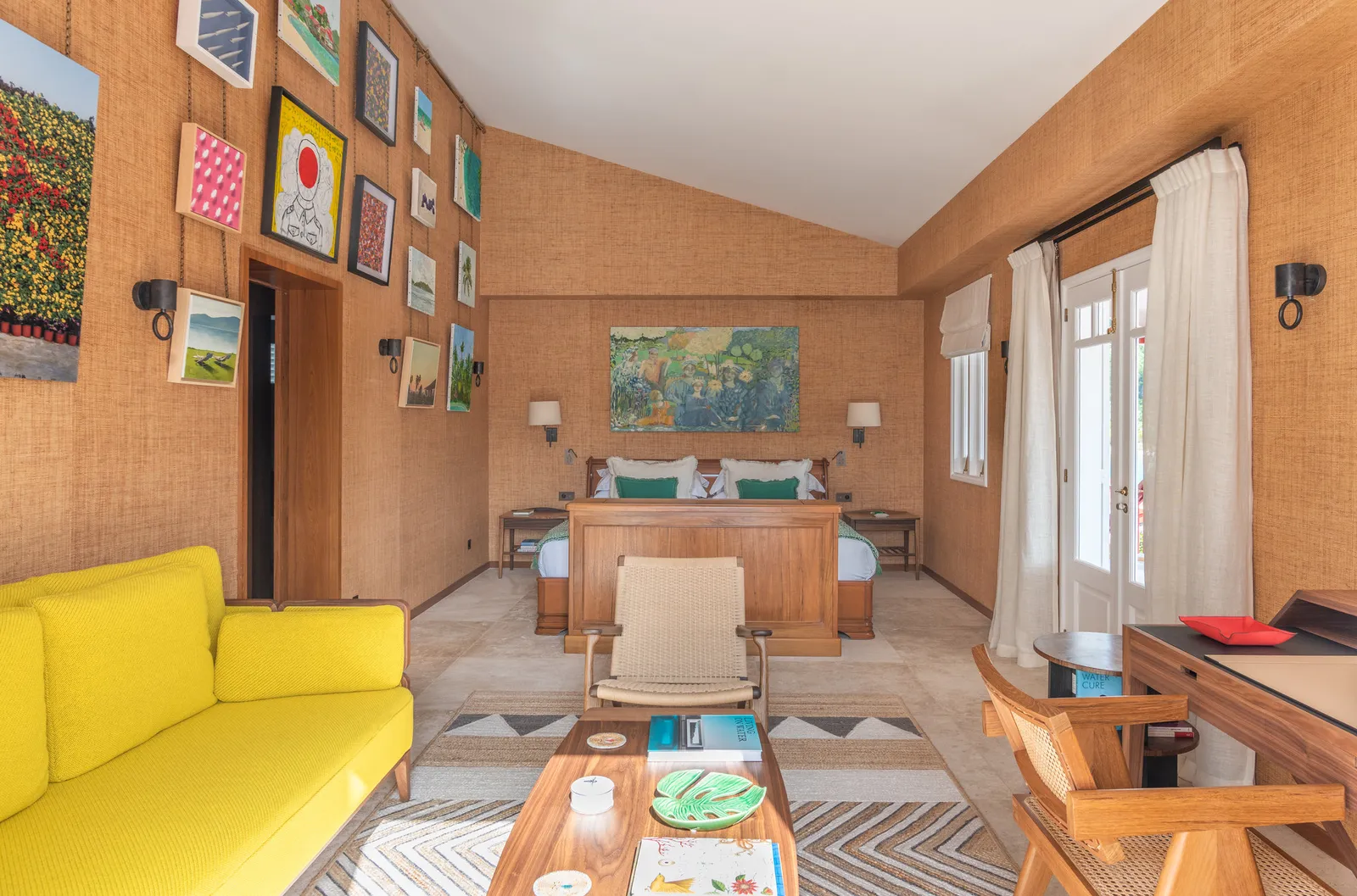 Rock Suite Treetops: a yellow sofa, a wall of framed pictures, the bed and white curtains at the French window.