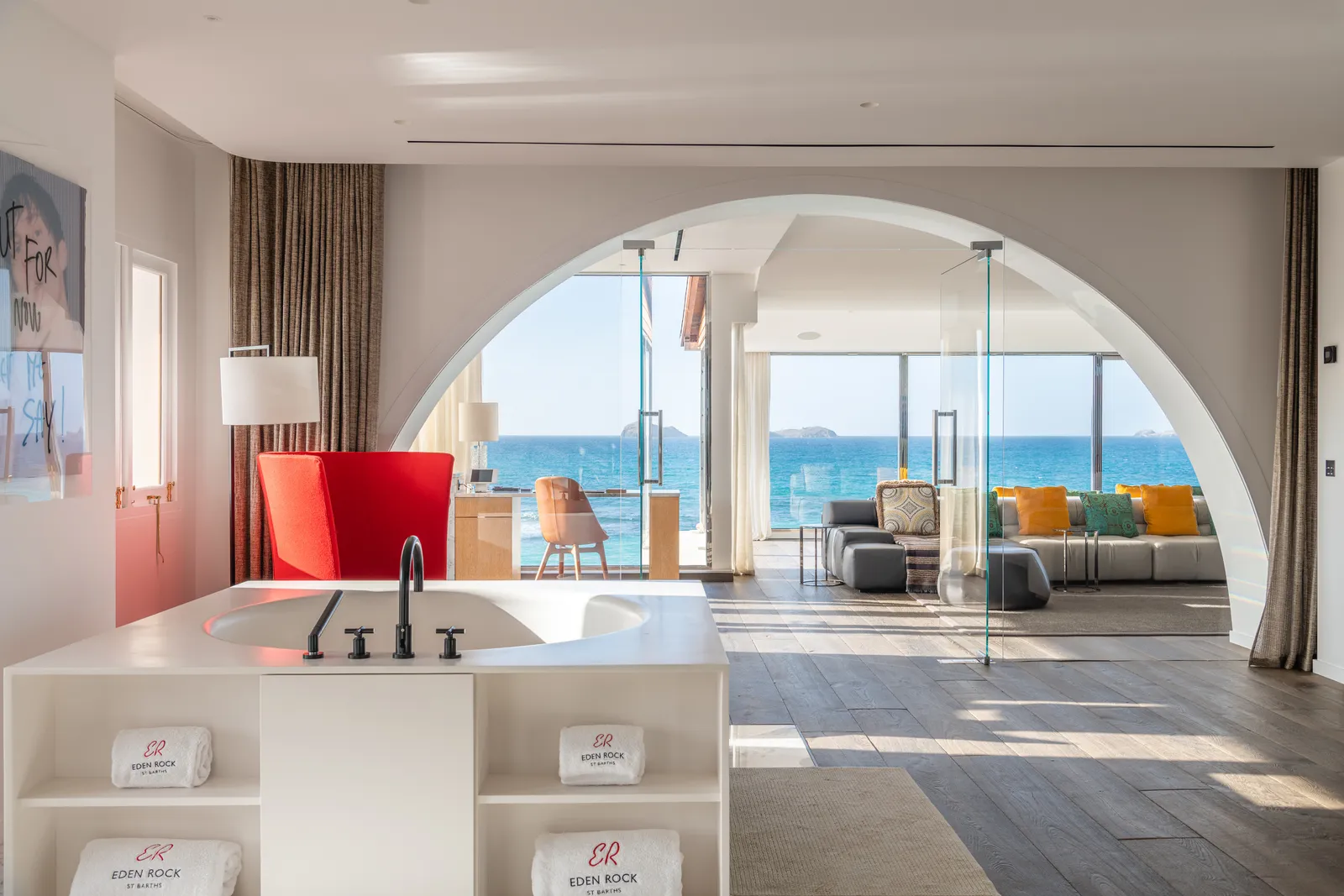 Signature Suite Christopher Columbus: the white bath in the foreground and, through a wide arch, the living room with its sofas and the sea.