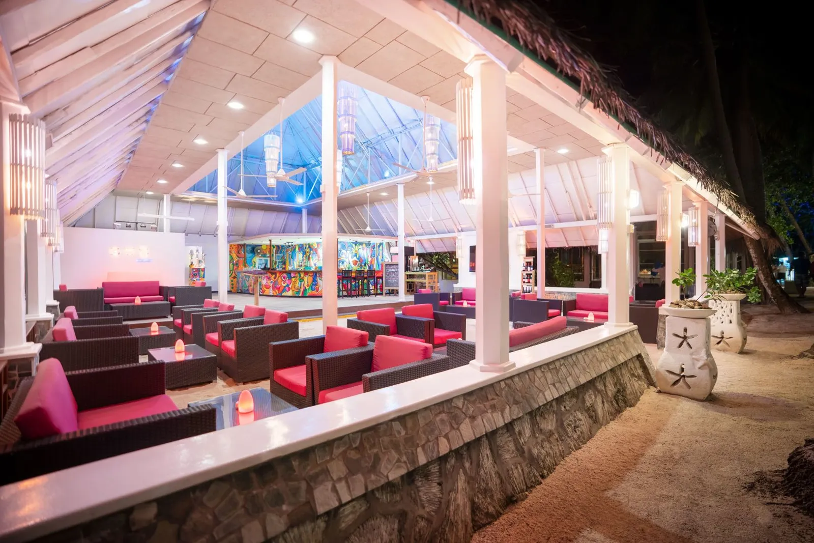 The bar at night, red armchairs under the lit roof