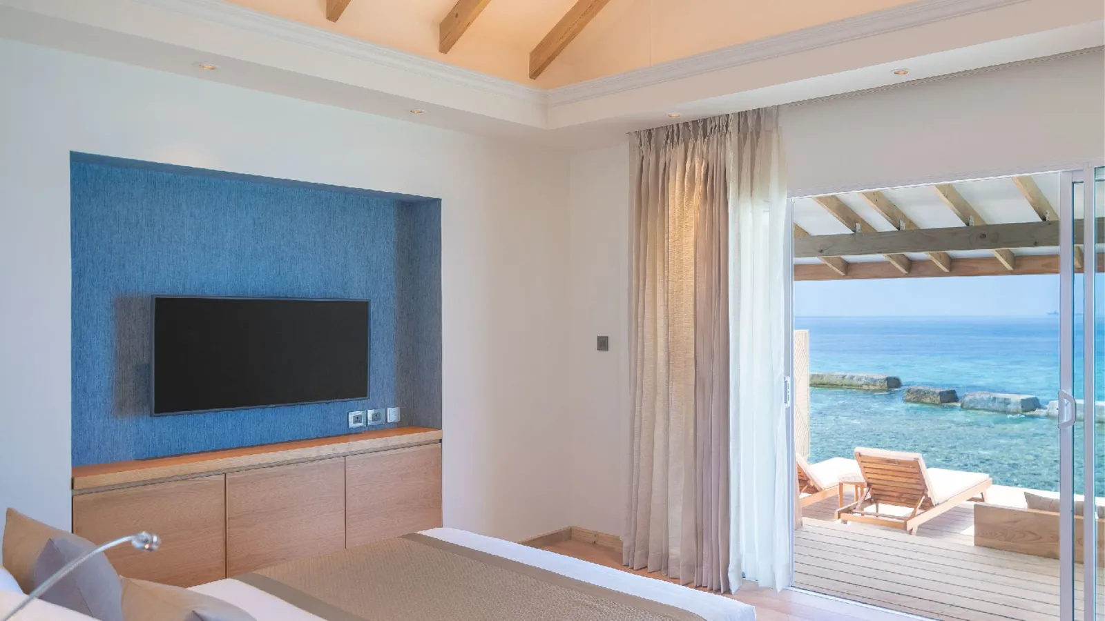 A Water Bungalow bedroom, its glass doors on the ocean