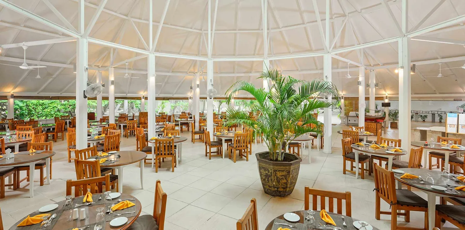 The main restaurant under its great white radiating roof, with the tables laid and a potted palm in the middle.