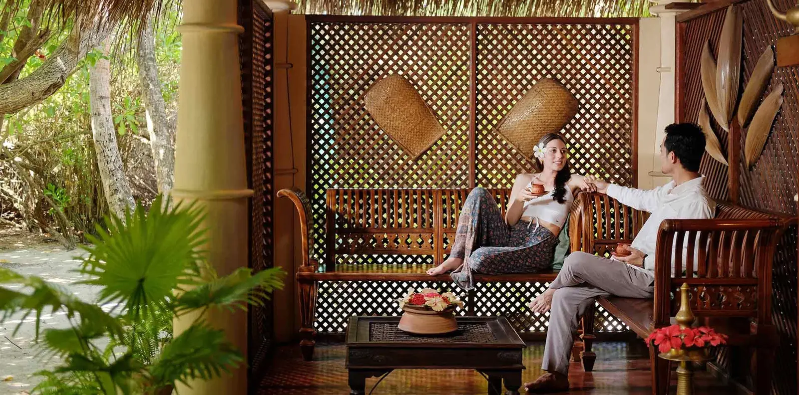 A couple on a carved wooden bench in the spa pavilion, in front of a lattice wall.