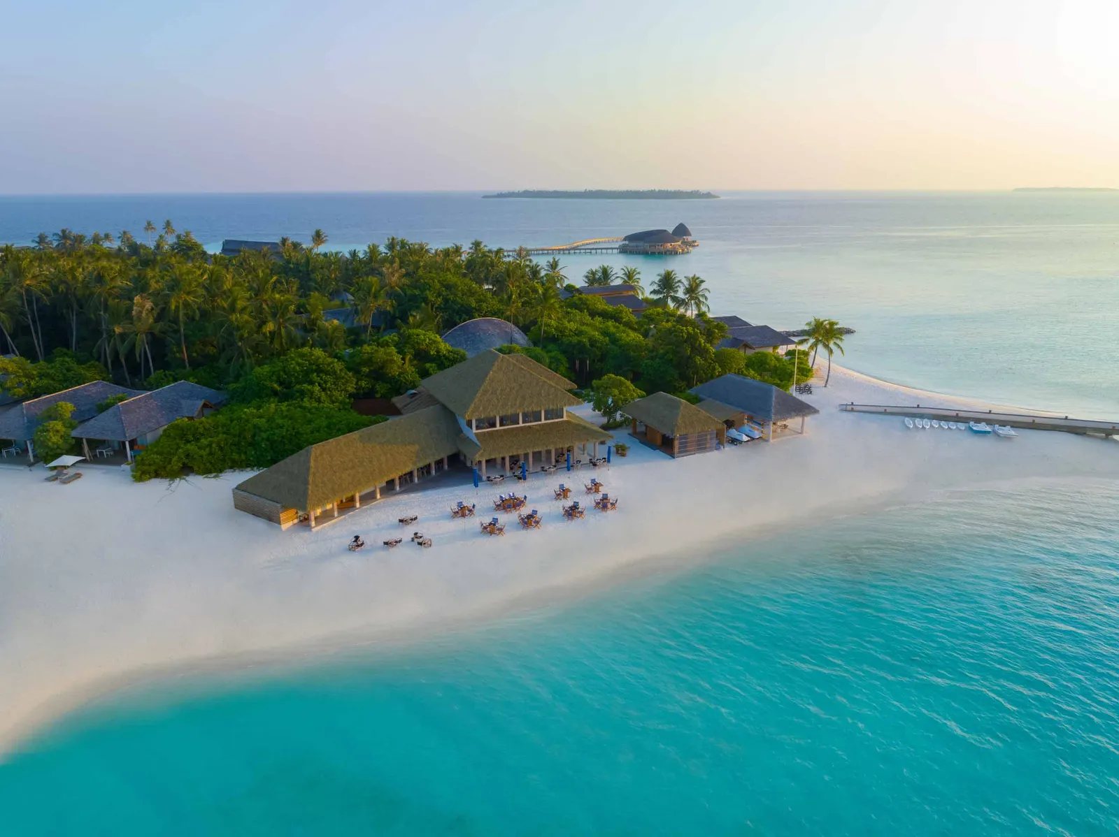The Beach Club Grill from above on the sandy point, tables on the beach and the island’s greenery behind.