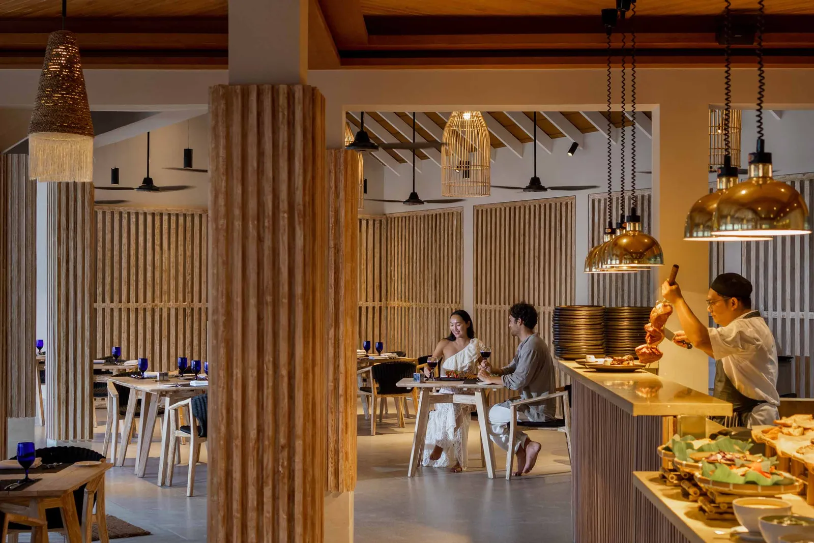 Carnivorous’s dining room, with laid tables, wicker lamps and a cook at the meat counter.