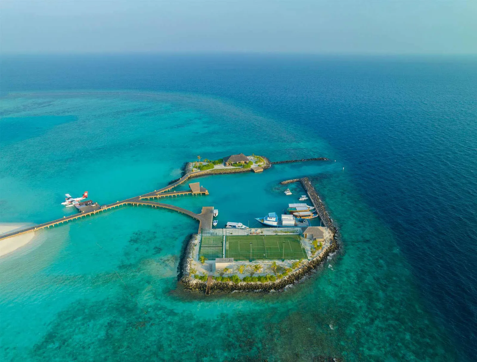 The marina from above: the seaplane at the jetty, boats in the harbour and the tennis court on the breakwater.