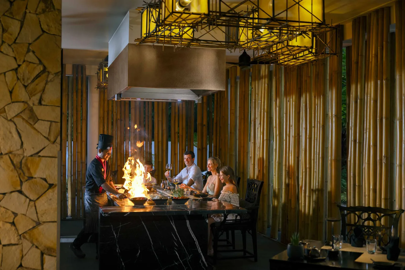 The teppanyaki at Le Asiatique: the cook sends up a flame in front of a family seated at the counter.