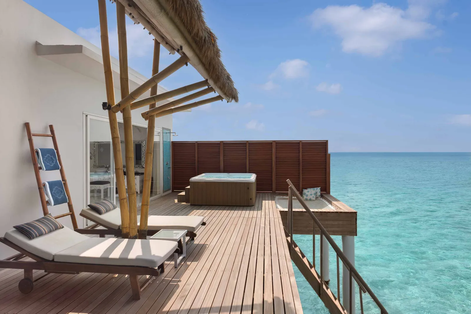 A Jacuzzi Water Villa’s deck, with its lounger, the hot tub and the turquoise sea.