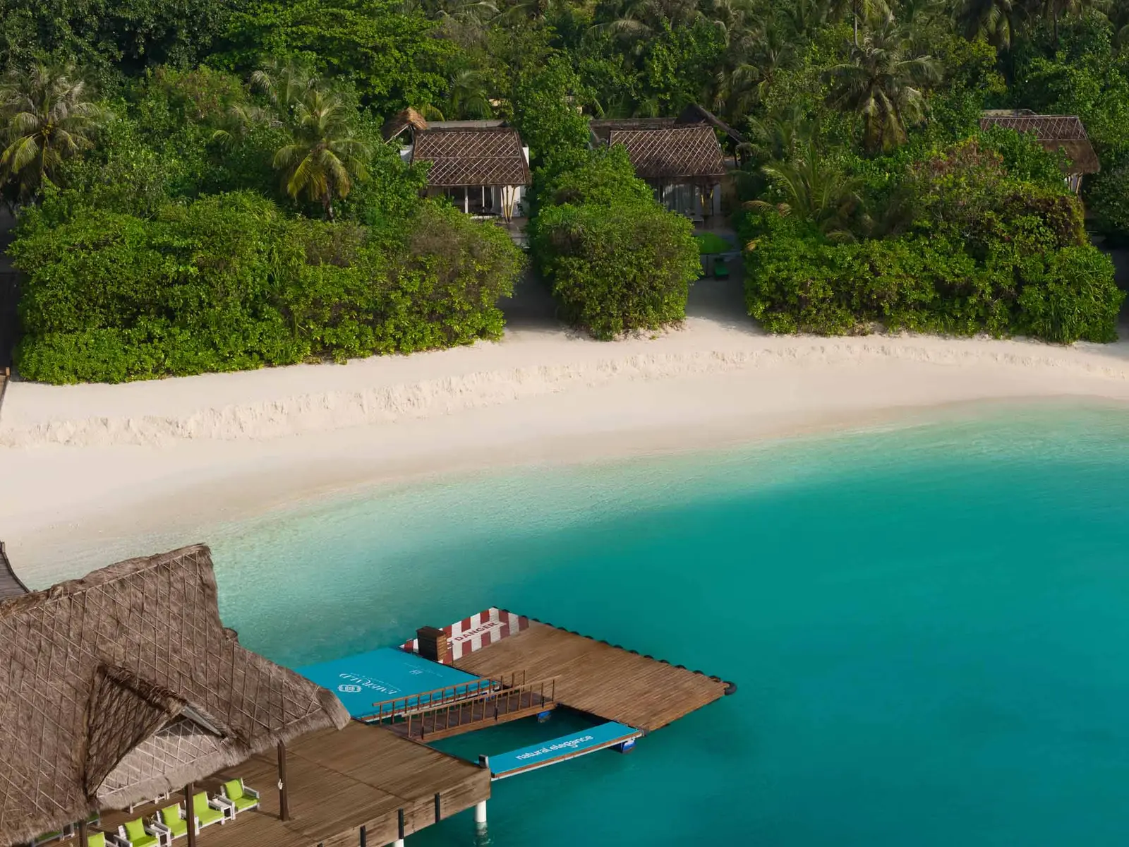 The marina villas from above, in the greenery over the beach, with the timber jetty on the lagoon.