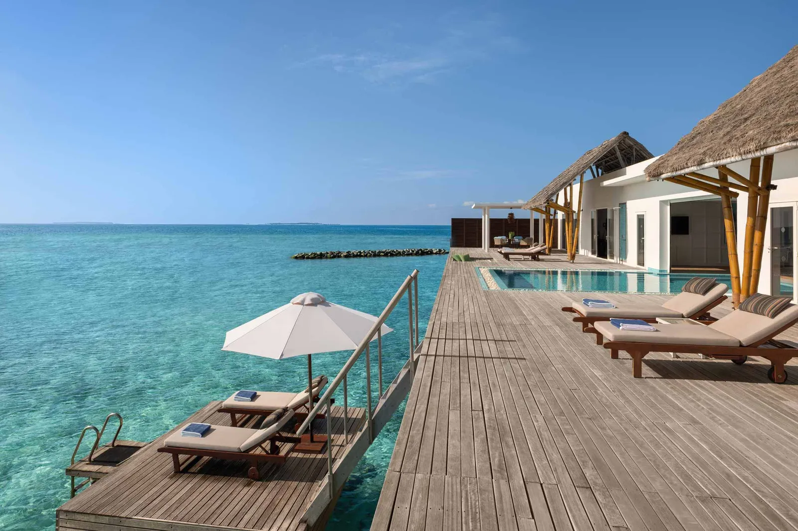 The long deck of the Presidential Ocean Villa, with its pool, loungers and parasol above the lagoon.