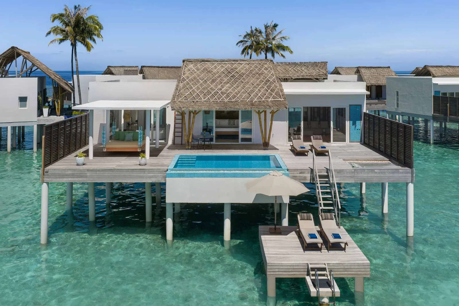 A Superior Water Villa seen from the sea, with the pool on its deck, loungers and the ladder into the lagoon.