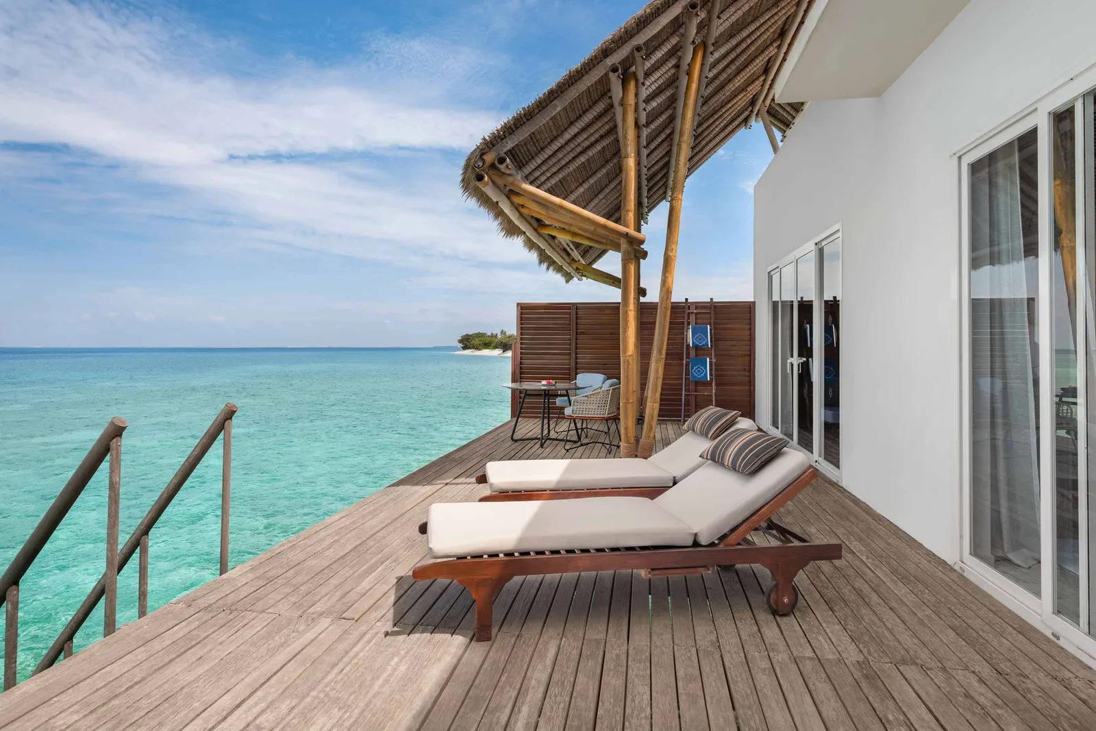 A Water Villa’s timber deck over the lagoon, with 2 loungers and the ladder down to the sea.