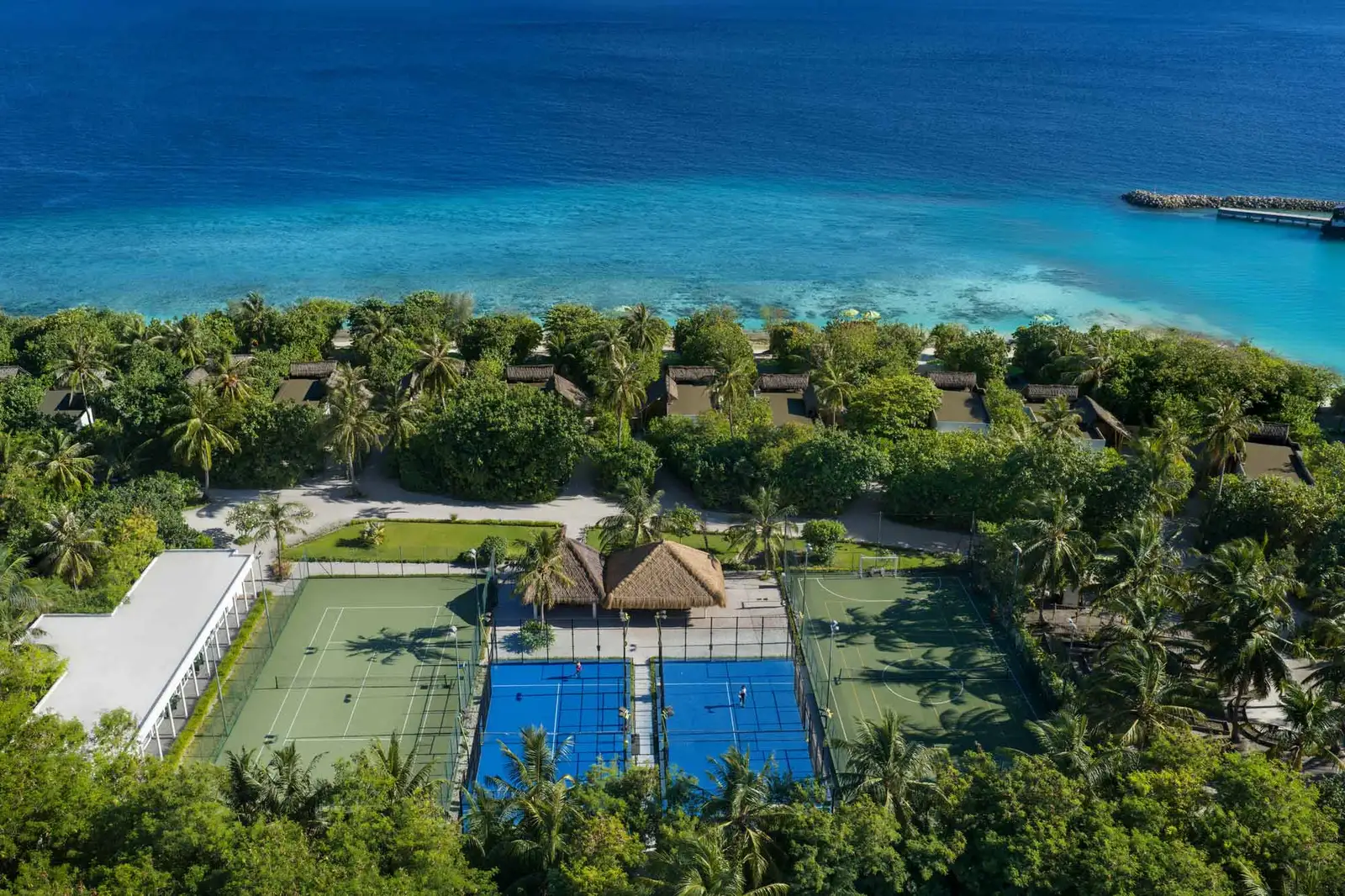 The tennis and padel courts from above, in the middle of the island’s greenery, the sea behind.