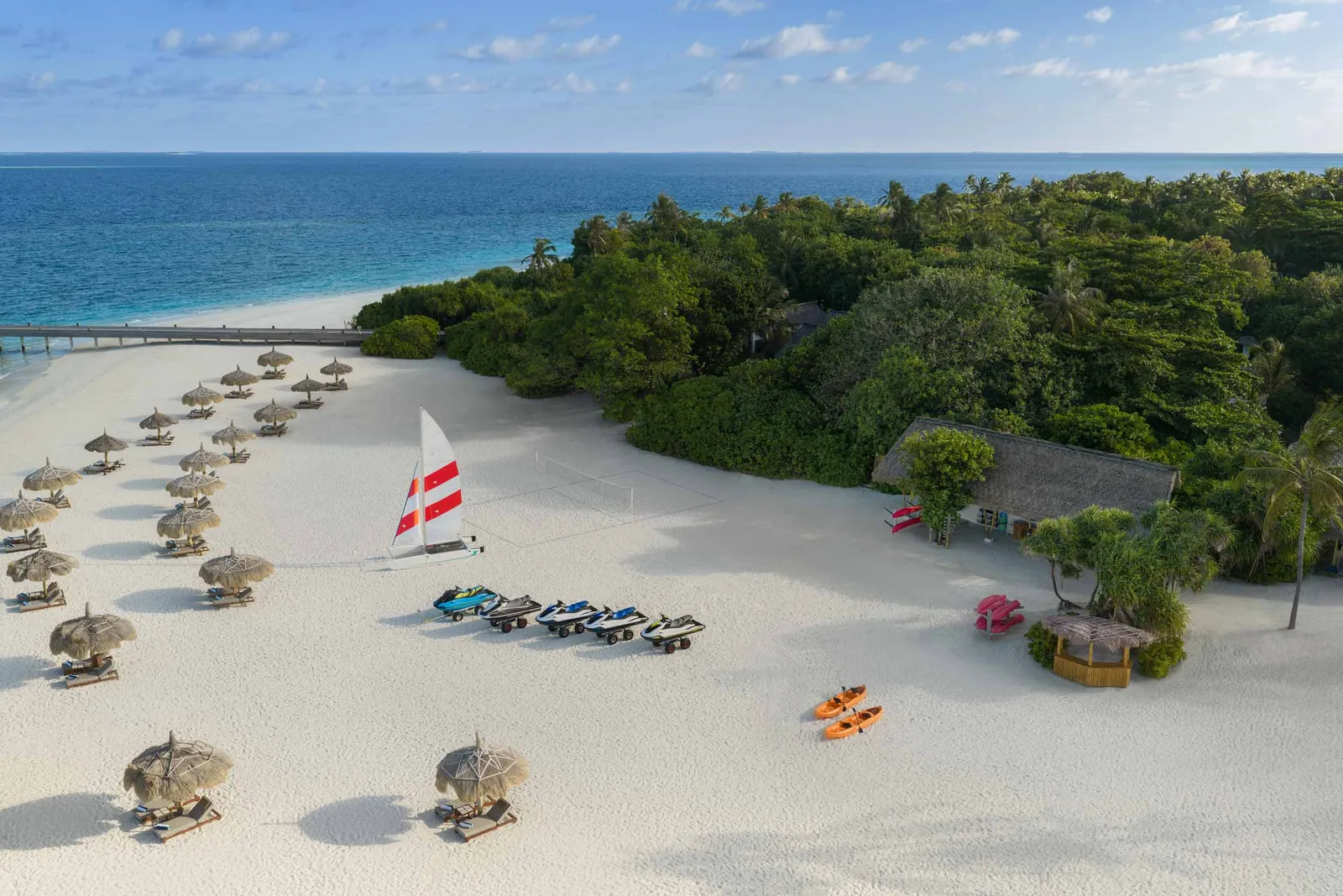 The water sports beach from above, with catamarans, kayaks and thatched parasols.