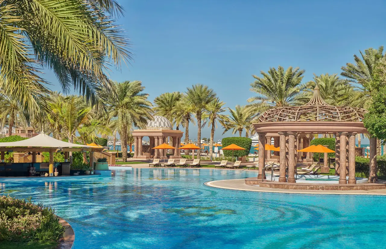 A pool among palms and the palace’s domed pavilions