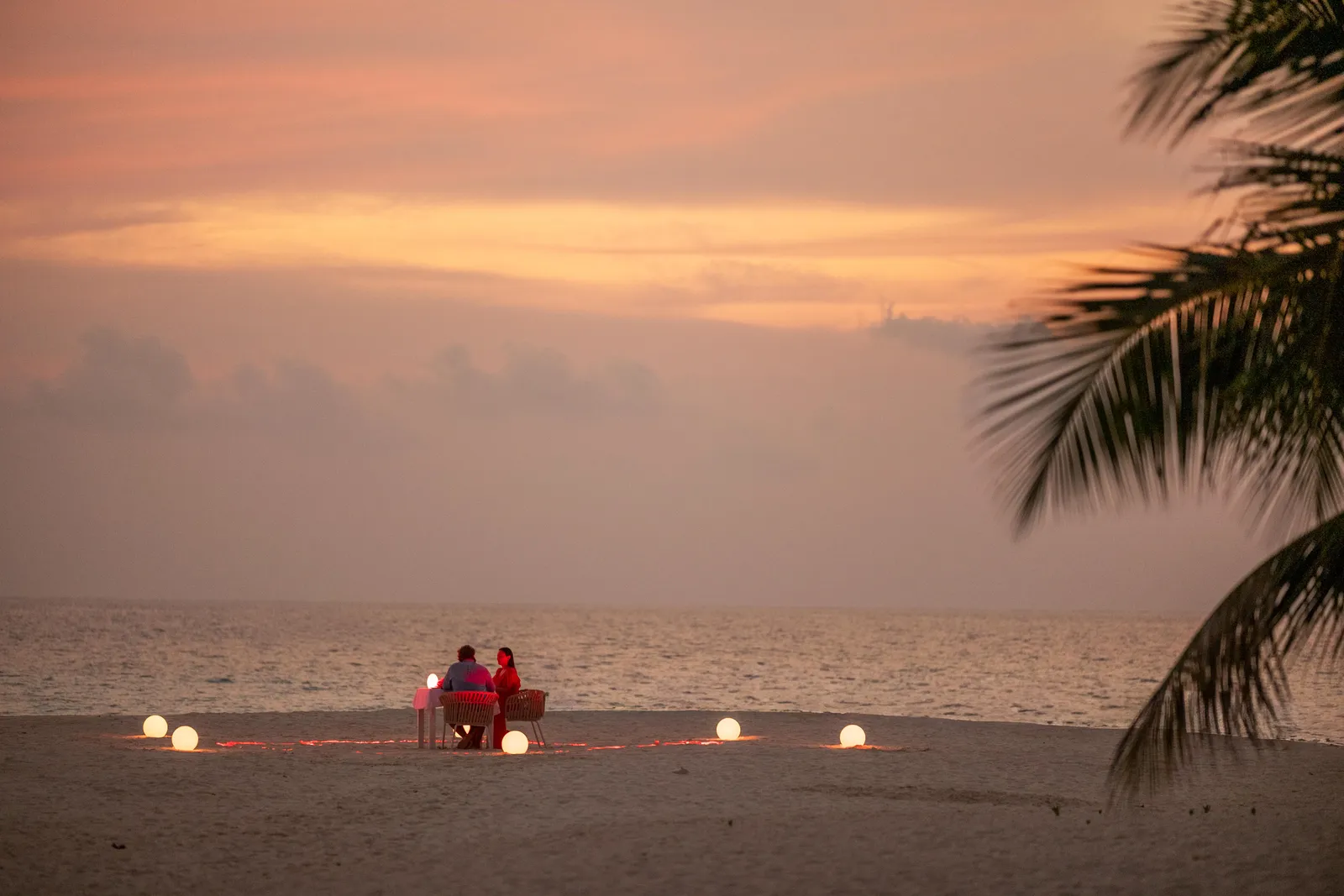 Dinner for 2 on the beach at sunset, among lanterns lit on the sand.